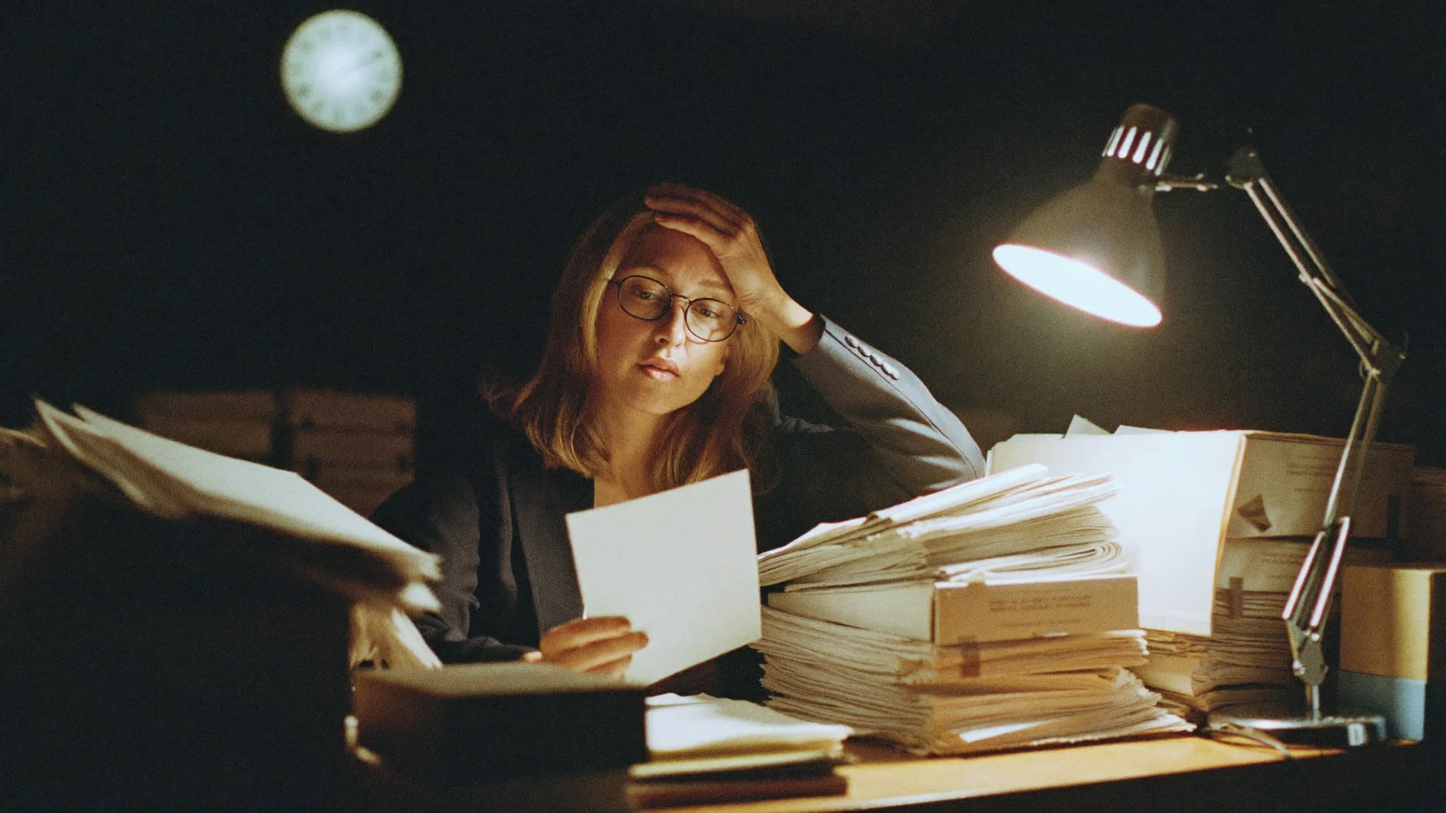 Heike nachts im Büro zwischen Papierstapeln